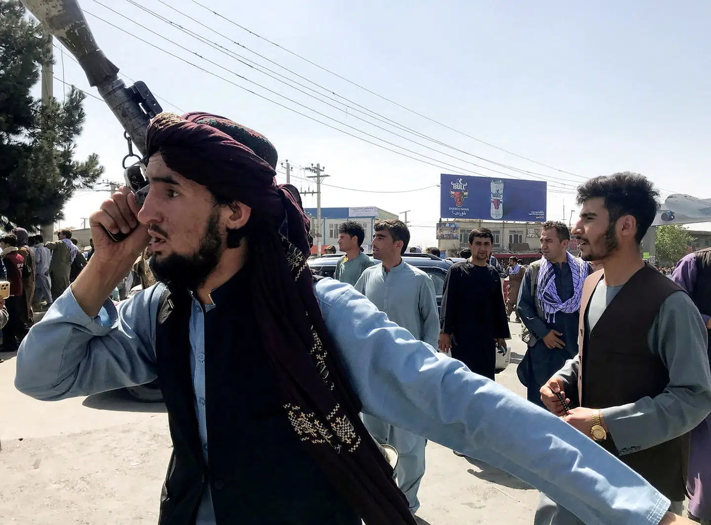 Et Taliban-medlem dirigerer med folk uden for lufthavnen i Kabul.