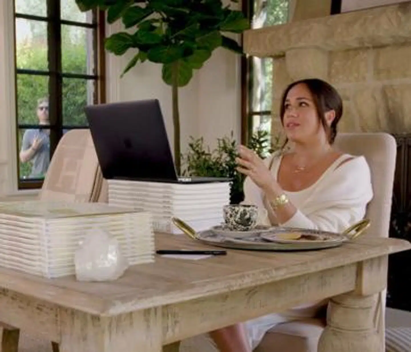 I baggrunden ser man pludselig prins Harry stå og jonglere i haven – til stor morskab for hans hustru og hendes virtuelle gæst.