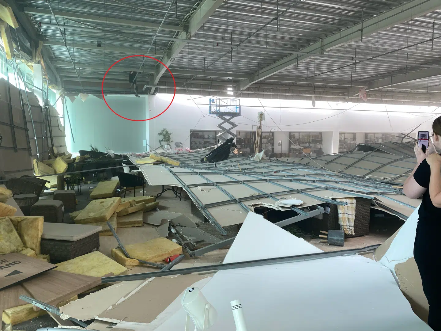 På et billede taget af en Ilva-kunde ses håndværkeren sidde på et rør mange meter over det sammenstyrtede loft.