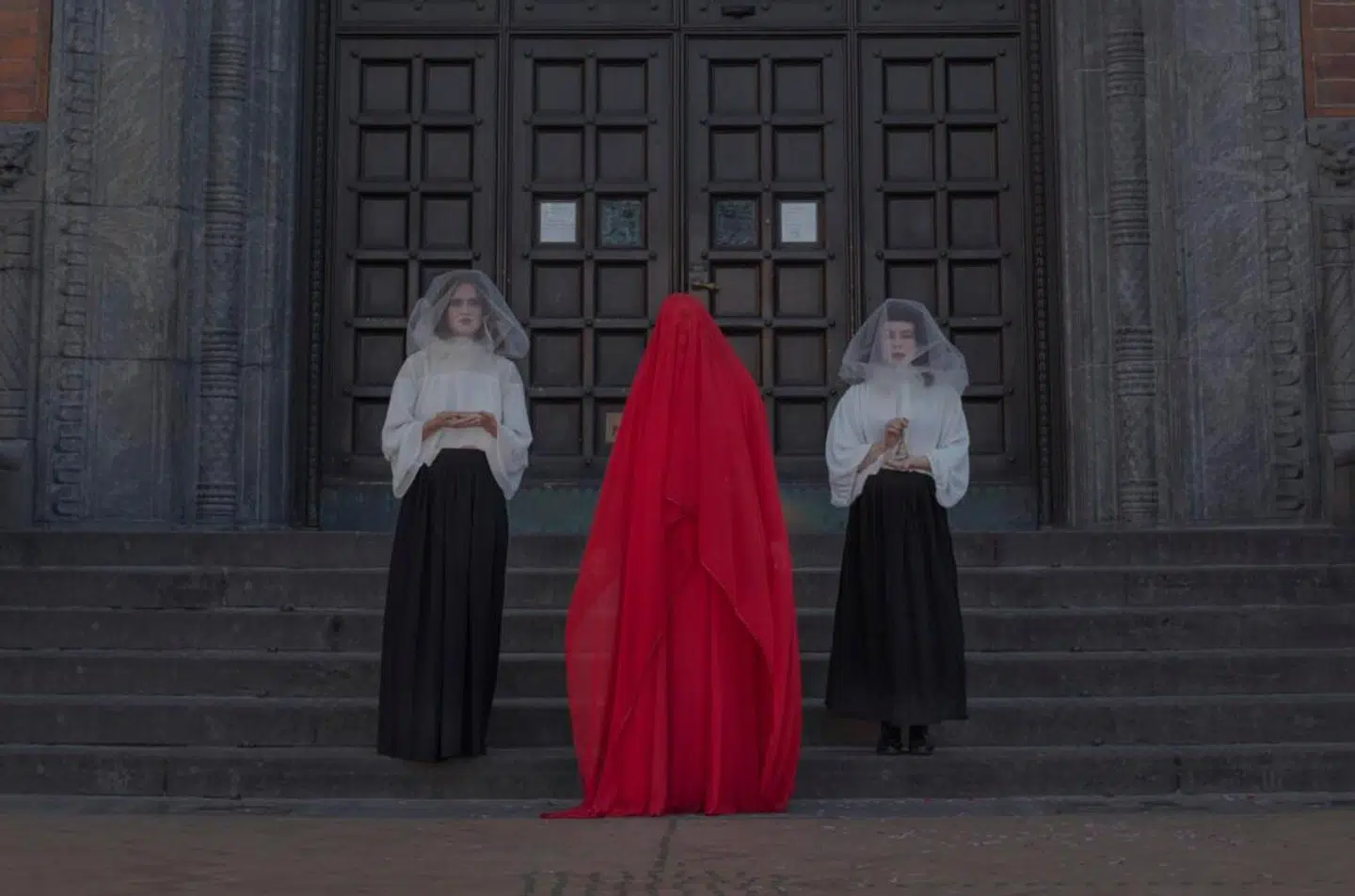 Den rød tilslørede vogterske er Gry Worre Hallberg, stifteren af performancegruppen Sister Hope, som her tager imod deltagere ved Københavns Rådhus, hvor den 24 timer lange vandring starter.