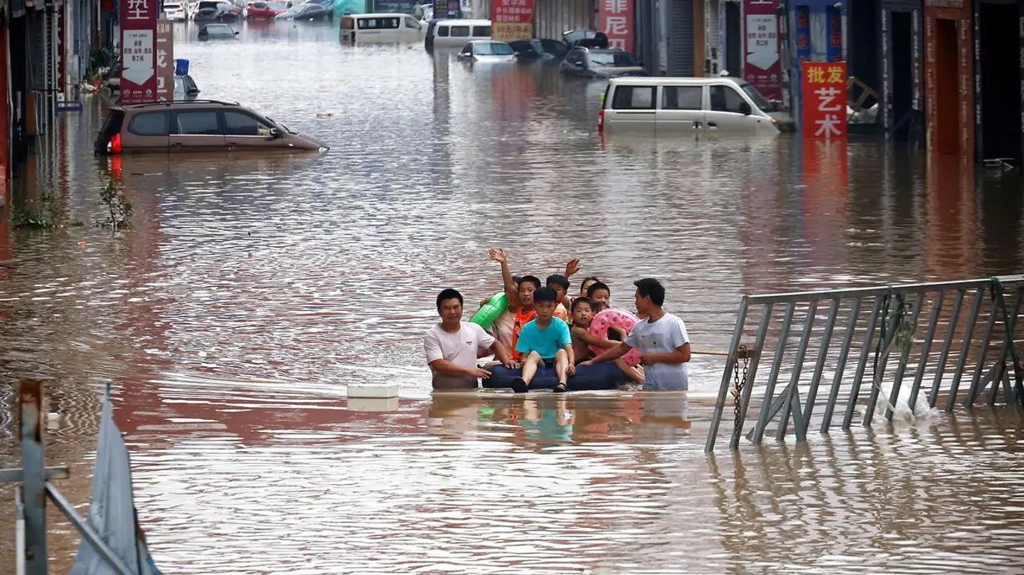Her kæmper nogle voksne sig væk fra vandet, mens børnene sidder på en luftmadras.