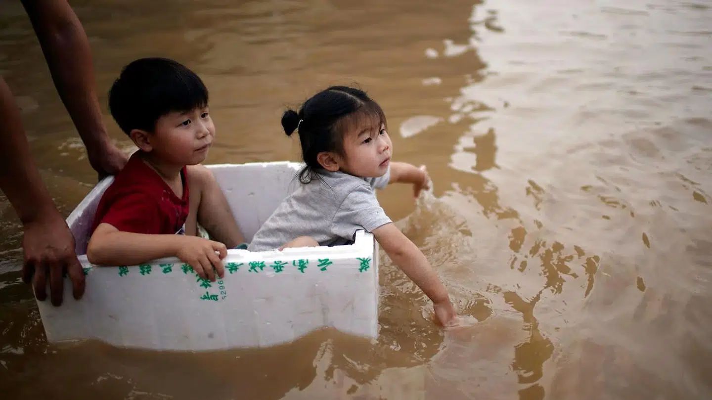 For at skåne børnene fra vandet, har nogle forældre her kommet dem op i en flamingokasse, mens de bevæger sig ud af byen.