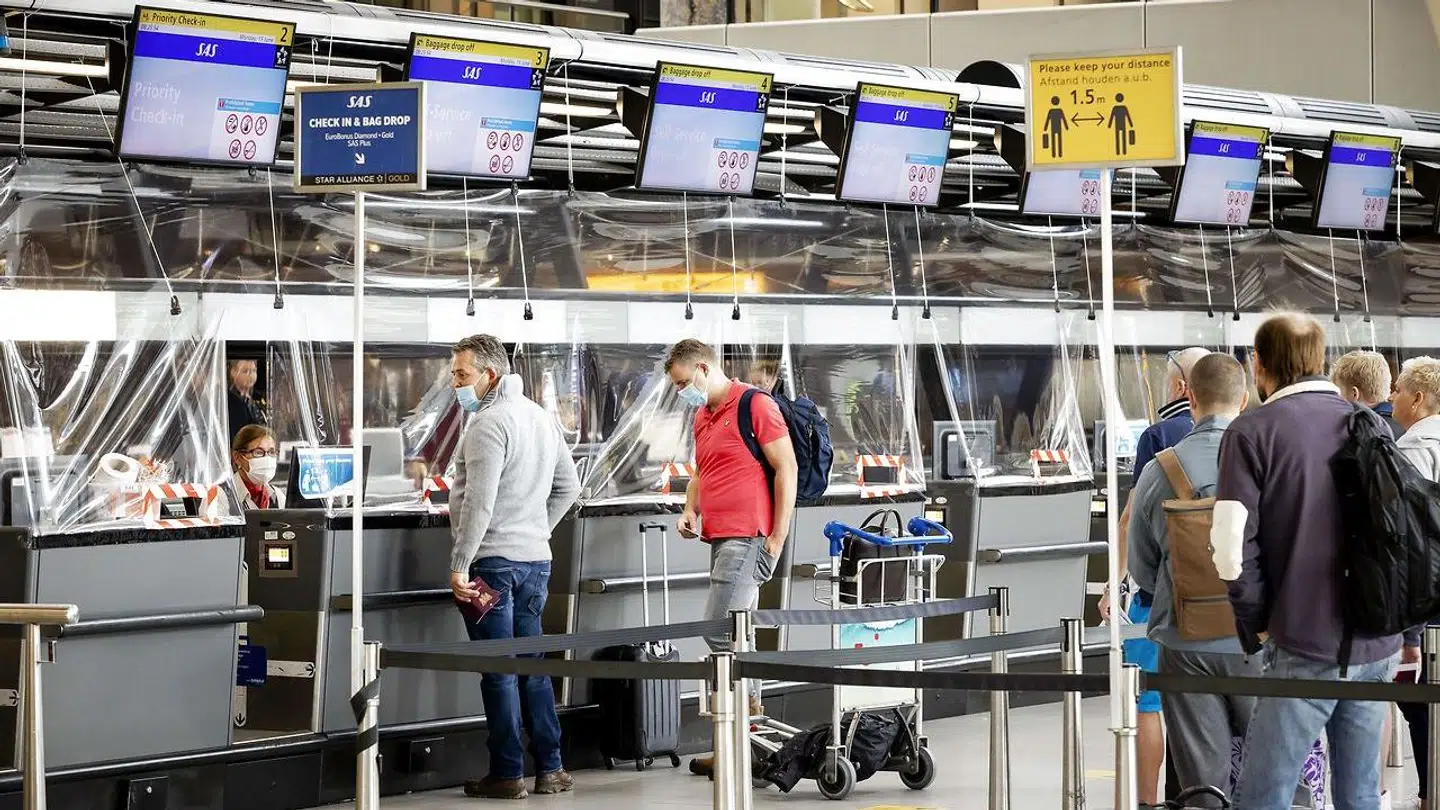 Passagerer står i kø til check-in. Det er fortsat obligatorisk at bære maske, når man opholder sig i en lufthavn.