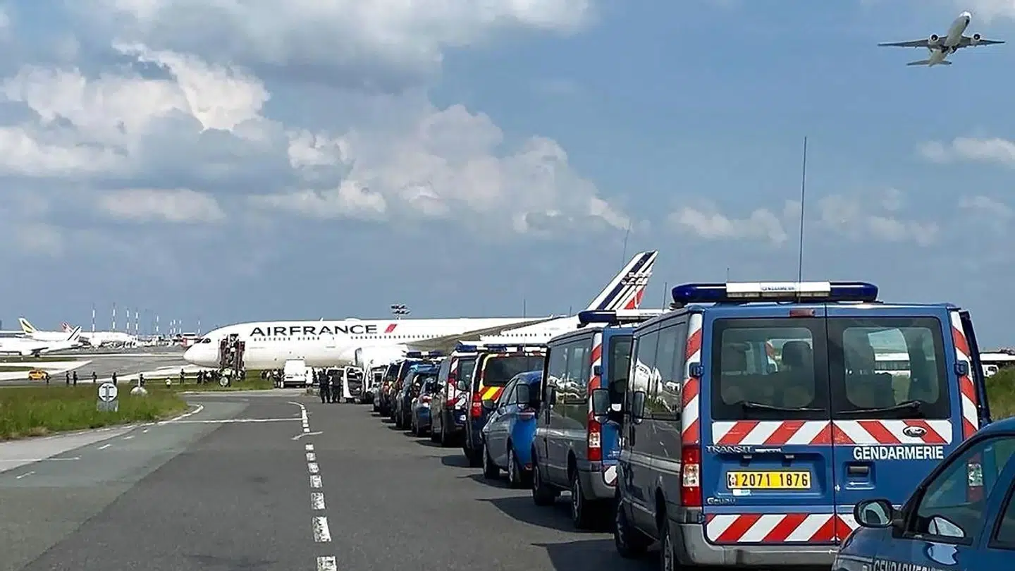Stribevis af franske politibiler linet op ved et AirFrance-fly i den franske lufthavn Charles de Gaulle. Flyet har modtaget en bombetrussel.