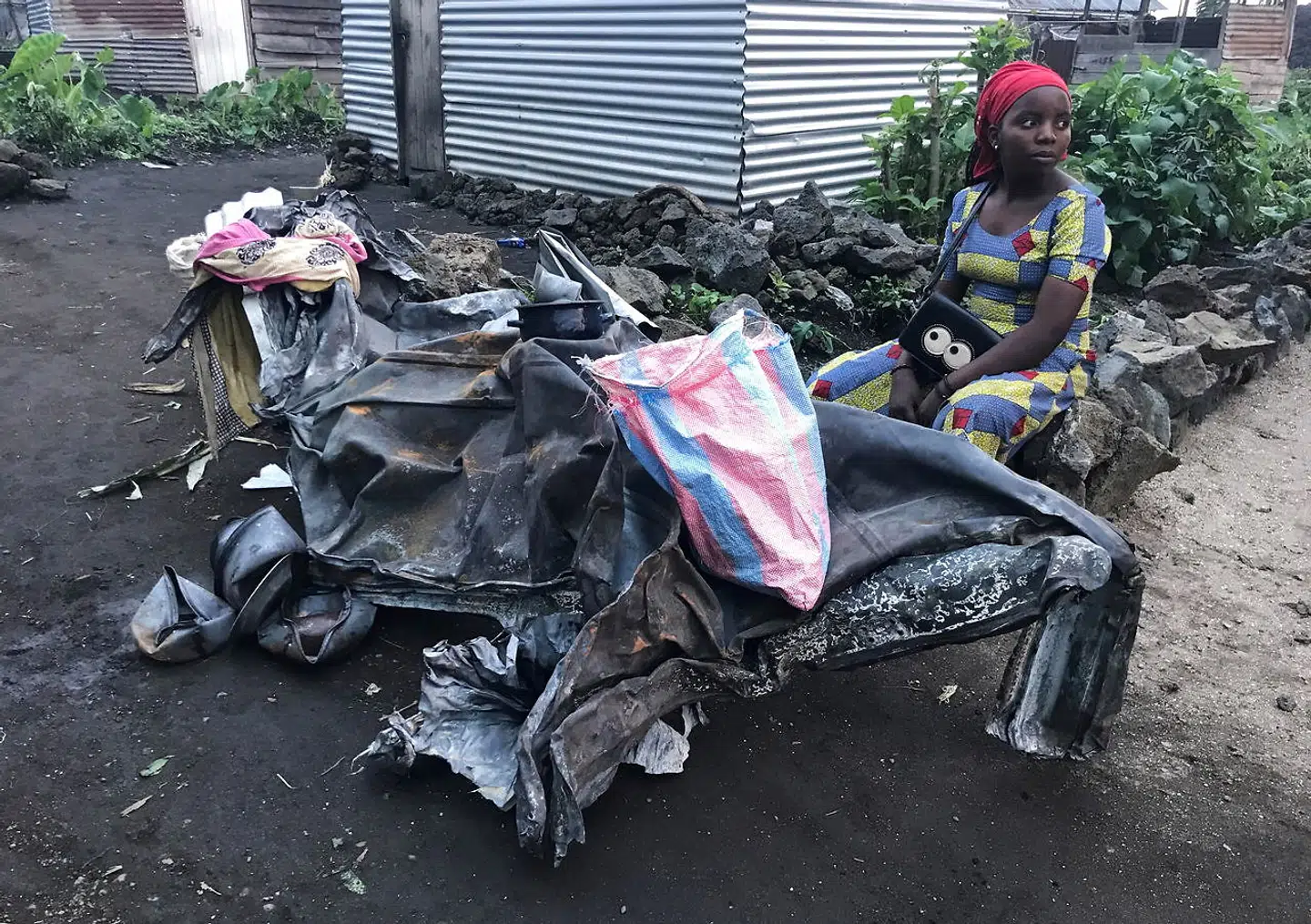 Den 22-årige Masika Joelle sidder ved siden af en udbrændt metalramme, som hun har reddet fra lavaen.