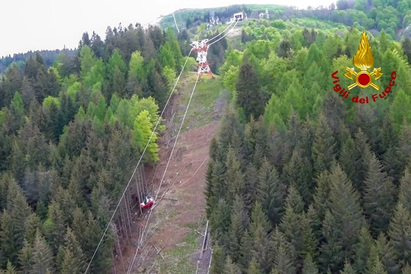 A photo grabbed from an aerial video taken on May 23, 2021 and handout on May 24, 2021 by The Italian Firefighters "Vigili del Fuoco" shows a cable car that crashed to the ground a few hundred meters below its arrival point at Mottarone peak above the resort town of Stresa on the shores of Lake Maggiore in the Piedmont region. - 14 people died on May 23 after a cable car crashed to the ground in northern Italy, emergency services said. (Photo by Handout / Vigili del Fuoco / AFP) / RESTRICTED TO EDITORIAL USE - MANDATORY CREDIT "AFP PHOTO / VIGILI DEL FUOCO / HANDOUT " - NO MARKETING - NO ADVERTISING CAMPAIGNS - DISTRIBUTED AS A SERVICE TO CLIENTS