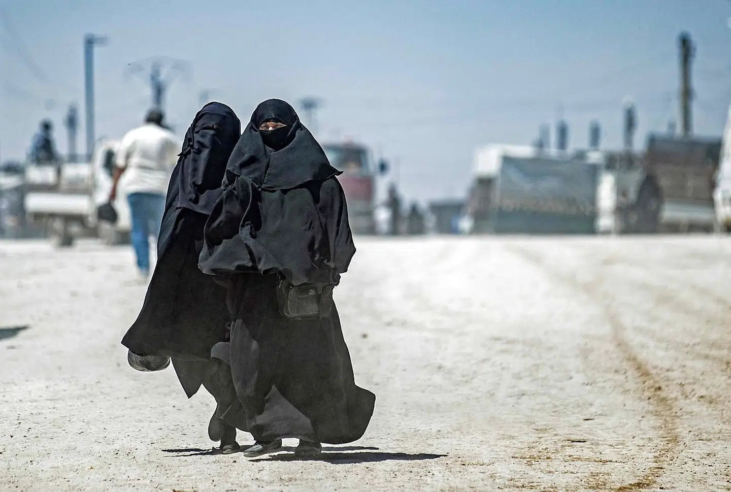 Women walk by as another group of Syrian families is released from the Kurdish-run Al-Hol camp, which holds relatives of suspected Islamic State (IS) group fighters, in the northeastern Syrian Hasakeh governorate, on May 11, 2021. (Photo by Delil SOULEIMAN / AFP)