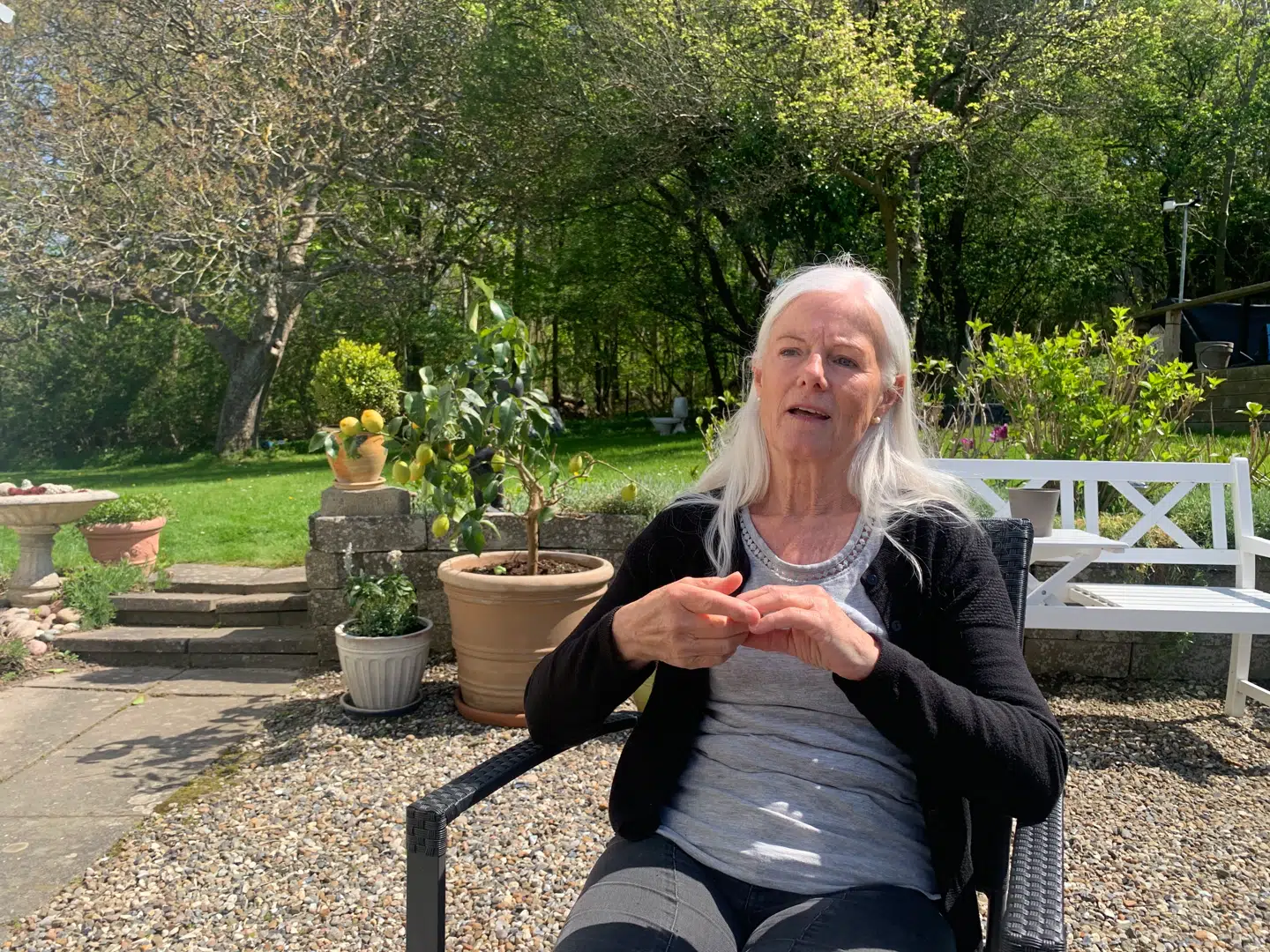 »Vi nyder hver eneste dag her. Og vi havde håbet på også fremadrettet at kunne gøre det. Men fra i dag ser det ikke sådan ud. Det er vores pensionisttilværelse, der skulle være her. Men bliver det her udrejsecenter en realitet, så bor vi ikke her mere,« siger Ida Tang.Bag hende træerne, som er det eneste, der adskiller hendes og hendes mands ejendom fra Holmgaard. Foto: Jens Anton Havskov