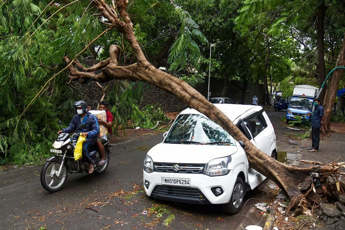 En motorcykel kører forbi en skadet bil i Mumbai den 18 maj 2021.