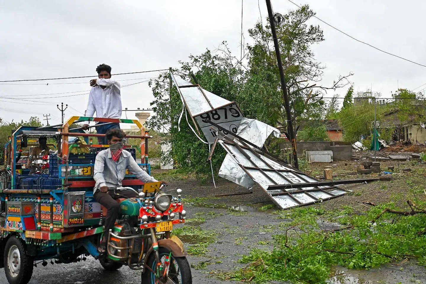 En rickshaw kører forbi et skadet skilt i Mumbai.