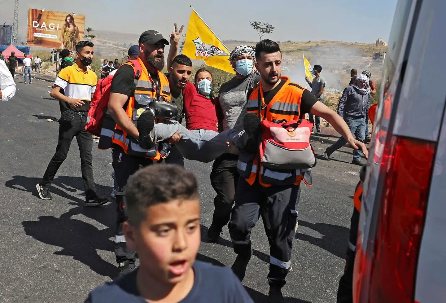 Palastinænsere bærer en såret mand væk fra gaden i Ramallah.