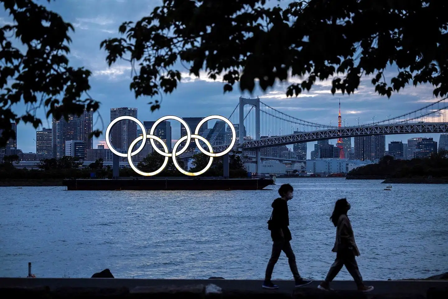 (FILES) This file photograph taken on April 28, 2021, shows a general view of the Olympic rings lit up at dusk on the Odaiba waterfront in Tokyo. - US drugs giant Pfizer and its German partner BioNTech on May 6, 2021, have announced a deal with the International Olympics Committee to provide vaccines to competitors and staff at the Tokyo games. In a statement, the firms said they would coordinate with national sporting bodies to make sure that coronavirus vaccines are available to anyone who needs one before travelling to Japan (Photo by CHARLY TRIBALLEAU / AFP)