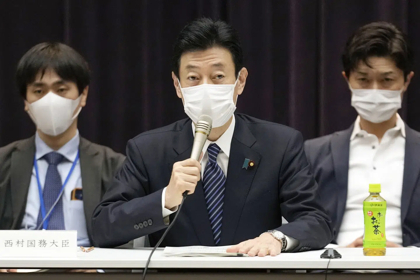 Japans økonomiminister, Yasutoshi Nishimura (i midten), præsenterede fredag yderligere restriktioner i landet. Unknown/Ritzau Scanpix