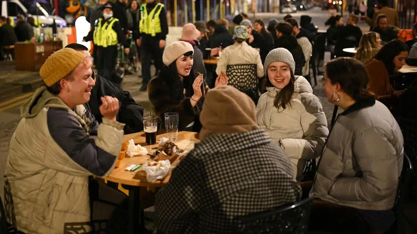 En gruppe unge nyder en øl på en bar i England, hvor vaccineudrulningen er gået en del strærkere end i Danmark.
