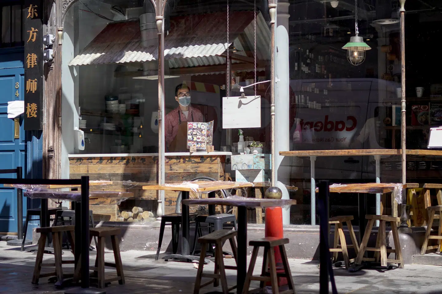 En ansat kigger ud fra vinduet fra en restaurant i Chinatown i London. Udendørs spisning er tilladt nu - og fra på mandag må gæsterne også rykke indendørs. Alberto Pezzali/Ritzau Scanpix