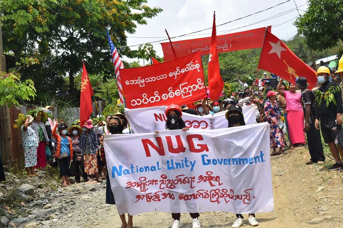 Demonstranter i delstaten Kachin i Myanmar holder bannere med opbakning til den samlingsregering, der er dannet af afsatte NLD-politikere og protestledere - National Unity Government (NUG). I Baggrunden blafrer det afsatte regeringsparti NLD's røde flag. Handout/Ritzau Scanpix