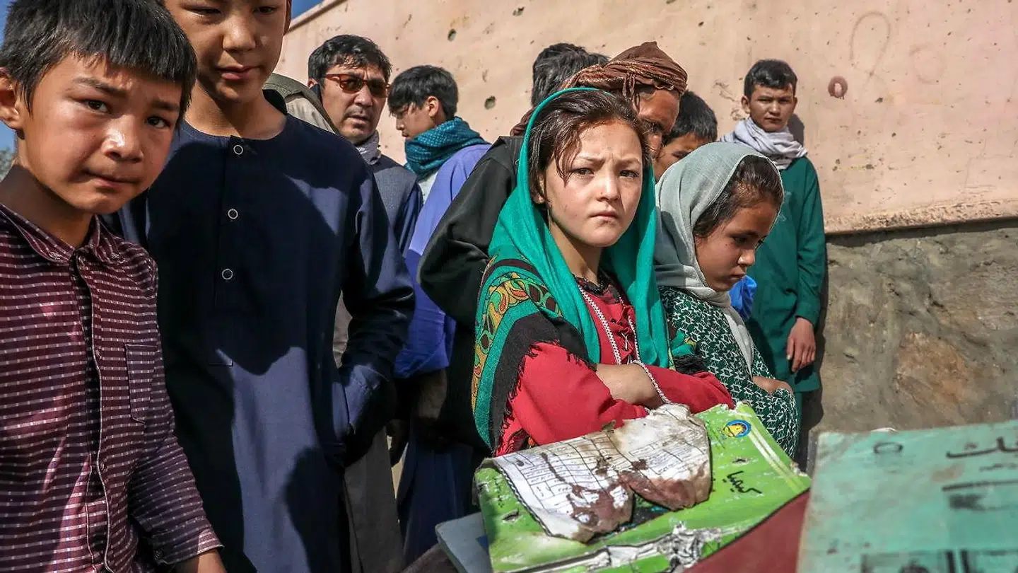 Overlevende kammerater til ofrene for eksplosionen foran en pigeskole i Kabul kigger på nogle af de forbrændte rester af ofrenes skoletasker.