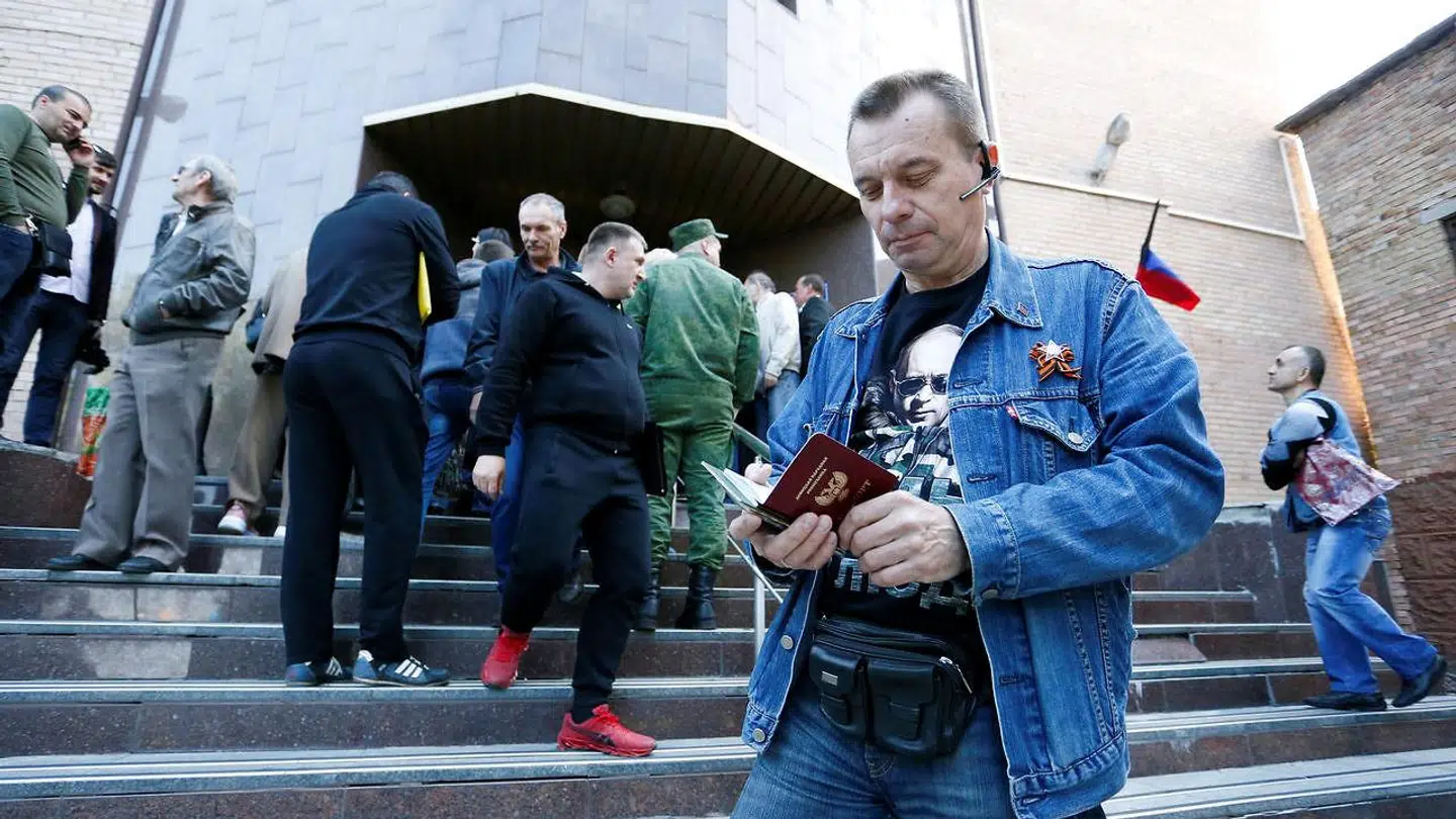 En mand i Donetsk i østlige Ukraine med Putin på sin t-shirt kigger på sit nye russiske pas, som han fik i 2019.