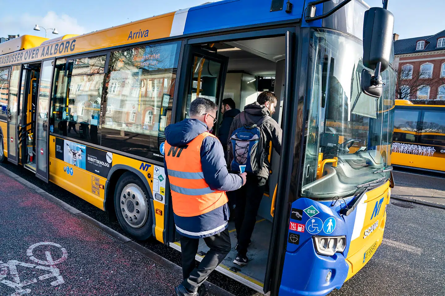 Guider fra Nordjyllands Trafikselskab deler løbesedler ud med advarsler om smittefare i overfyldte busser ved busterminalen i Aalborg, 11. marts 2020.. (Foto: Henning Bagger/Ritzau Scanpix)