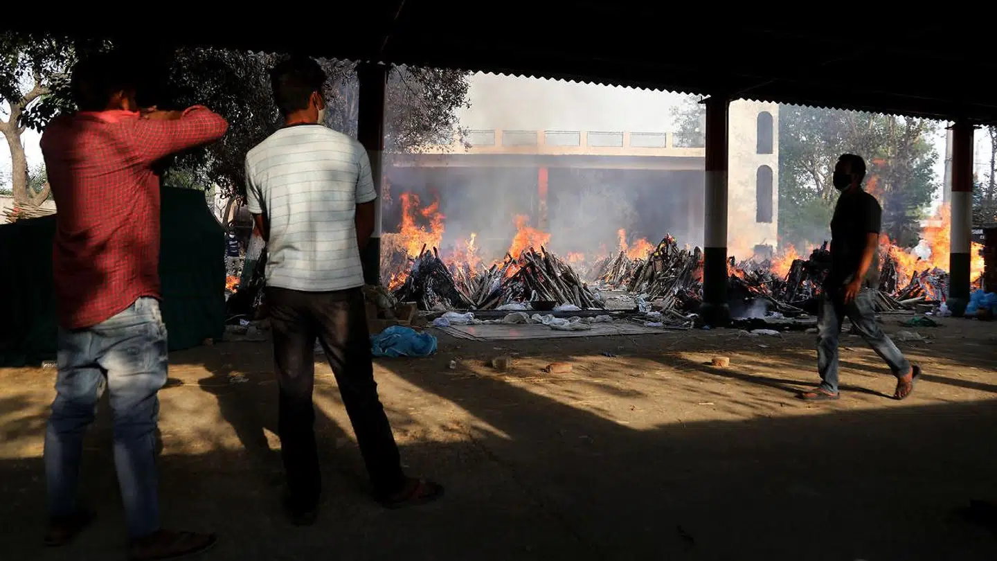 Pårørende ser til mens corona-ofre brændes ved hastigt planlagte masseafbrændinger. (Foto: Scanpix)