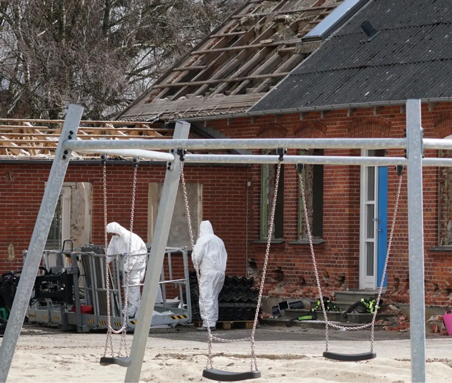 Nedrivningsarbejdere render rundt i hazmat-dragter, få meter fra hvor skolebørnene leger. Foto: Marianne Høj Ahlers.