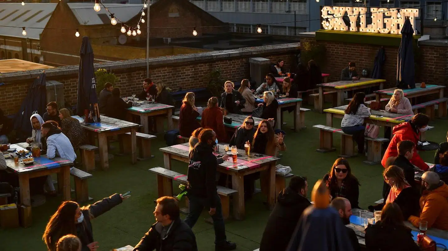 Folk nyder solnedgangen ved tagbaren Skylight. London 12. april 2021.