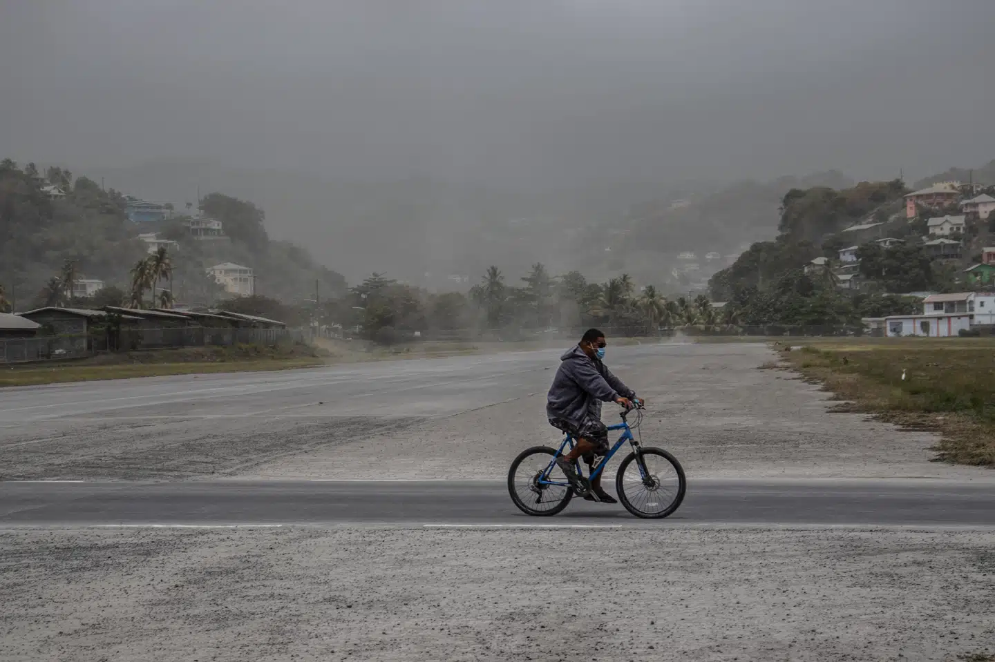 En beboer cykler forbi askedækkede marker i hovedstaden Kingstown. Lucanus Ollivierre/Ritzau Scanpix