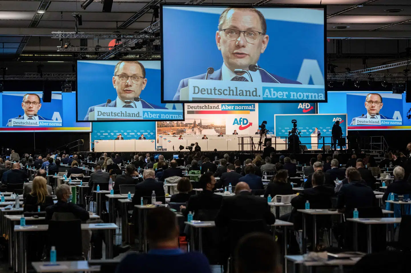 De forsamlede ved Alternative für Deutschlands partimøde sad med afstand og flere med mundbind. 570 mennesker deltog i lørdagens partikongres i Dresden. Her er det en af partiets formænd, Tino Chrupalla, der taler. Mødet fortsætter søndag. Jens Schlueter/Ritzau Scanpix