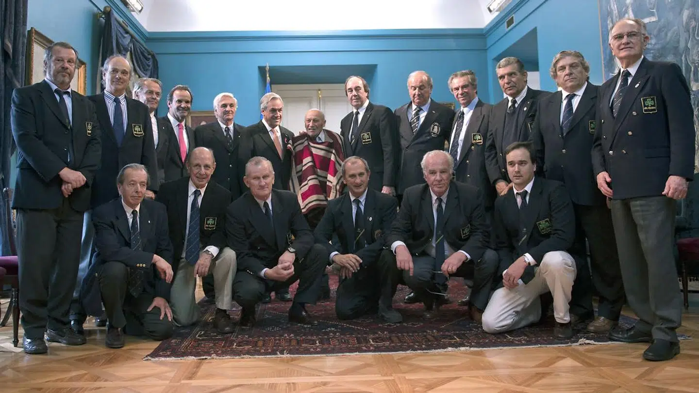 Her ses de 16 overlevende flypassagerer sammen med den chilenske præsident og én af dem, der reddede dem ud af Andesbjergene, i oktober 2012. Foto: Martin Bernetti/AFP