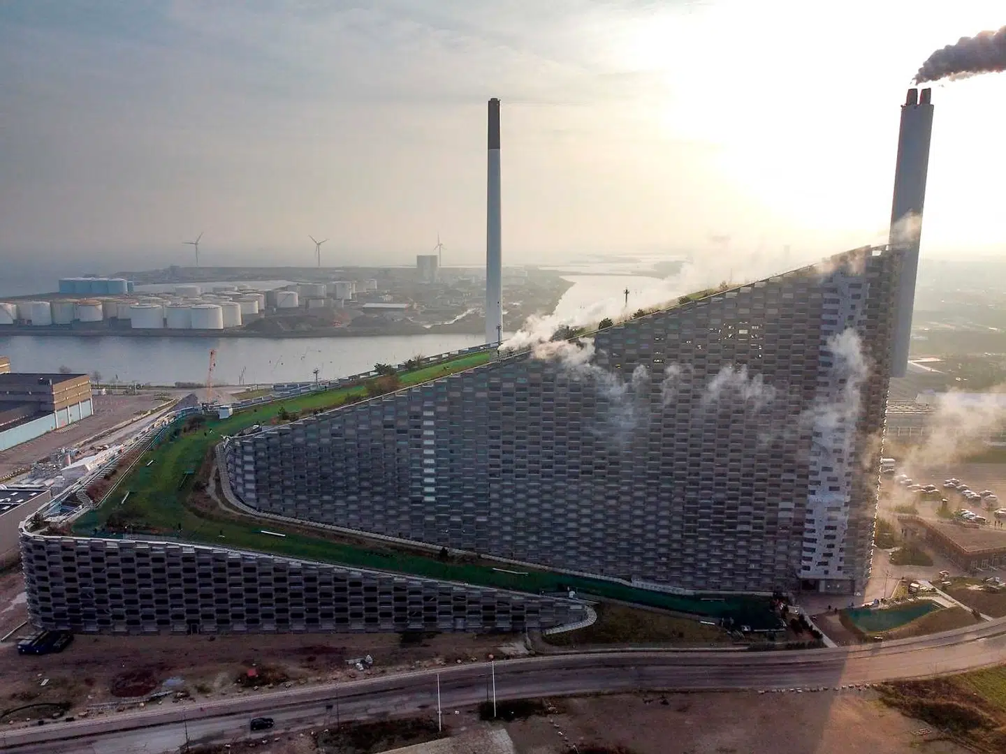 People ski down the artificial ski hill on the Outdoor structure CopenHill, December 6, 2020 in Copenhagen. - CopenHill is an urban mountain placed on top af a state-of-the-art waste-to energy plant, ARC, which is one of the most unique architectural designs in the world. The plant produces environmental-friendly energy with the newest technology by burning waste and turning the exhaust into energy which yearly provides the city of Copenhagen with electricity for 30, 000 households and central heating for 72, 000 households. The structure has a ski hill, a hiking track and a climbing wall. (Photo by Olivier MORIN / AFP)