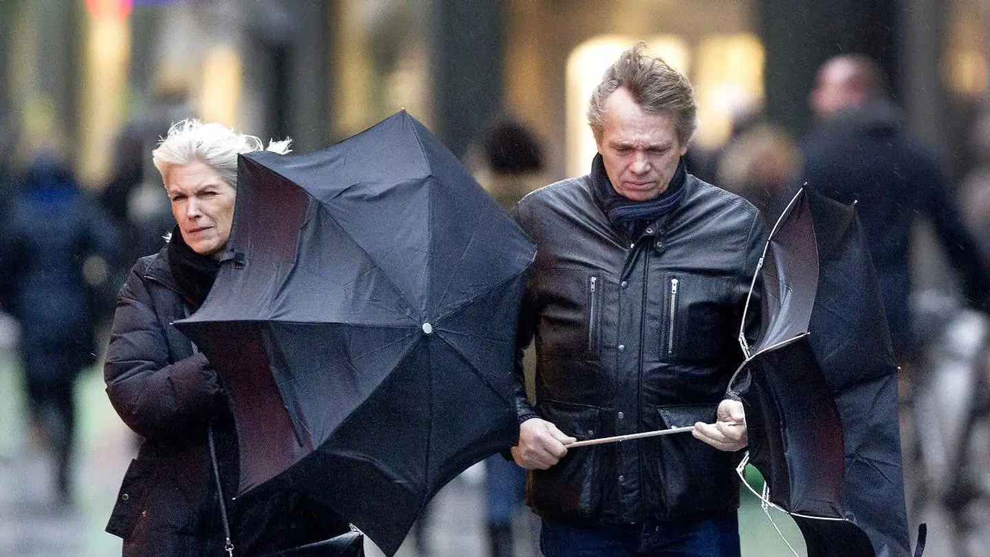 Personer går i blæsevejr på Strøget i København.