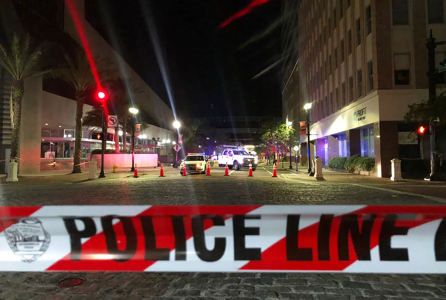 This photo shows a police car behind police tape blocking a street leading to the Jacksonville Landing area in downtown Jacksonville, Florida, August 26, 2018, where three people were killed, including the gunman, and 11 others wounded. Two people were killed and 11 others wounded on August 26 when a video game tournament competitor went on a shooting rampage before turning the gun on himself in the northern Florida city of Jacksonville, local police said. Sheriff Mike Williams named the suspect of the shooting at a Madden 19 American football eSports tournament as 24-year-old David Katz from Baltimore, Maryland. Gianrigo MARLETTA / AFP