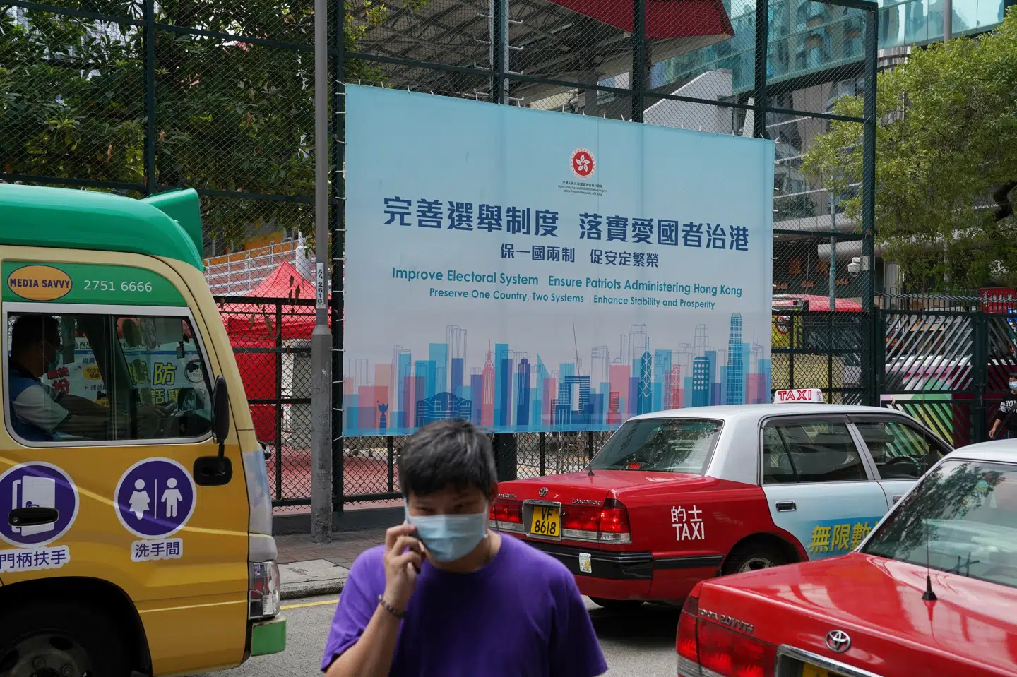 Forbedr valgsystemet, står der på en plakat fra regeringen, som en mand går forbi i Hongkong, kort efter at reformer blev vedtaget. Lam Yik/Reuters