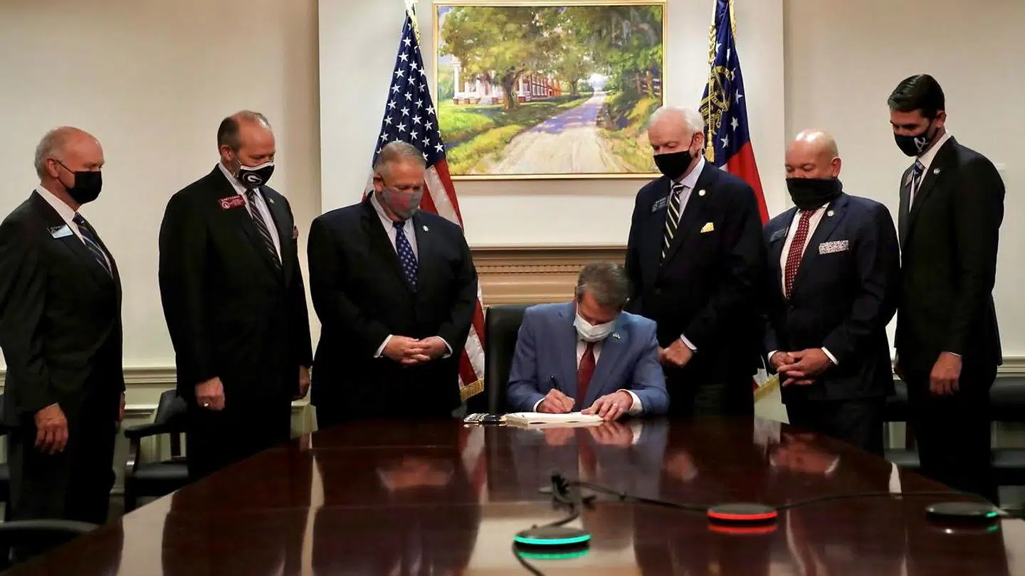 Den republikanske guvernør i Georgia, Brian Kemp, i gang med at underskrive den lov, som Park Cannon er stærkt utilfreds med.