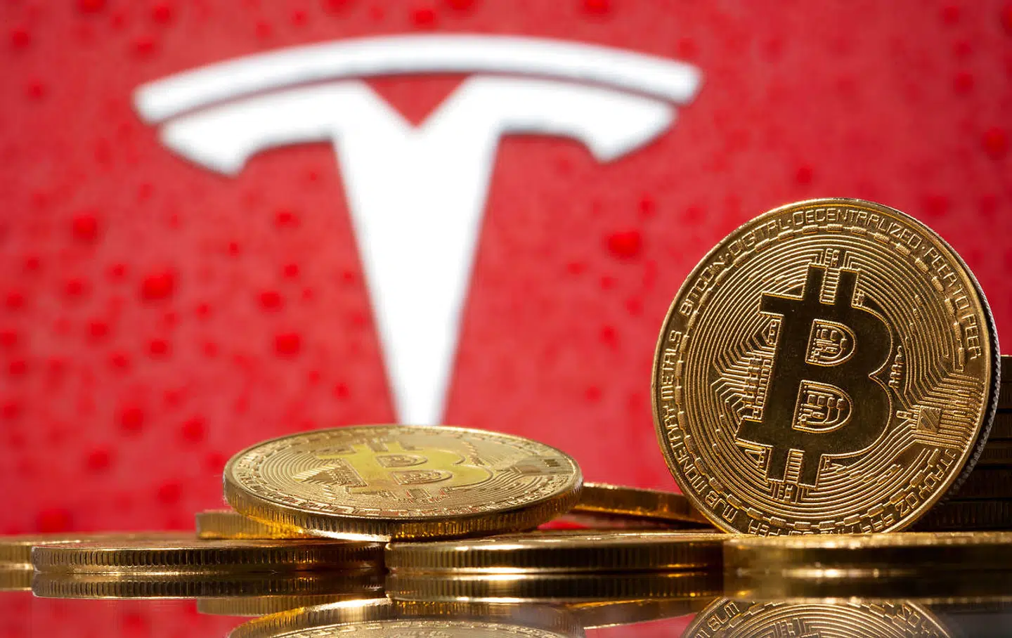 En bitcoin foran Tesla-logoet.