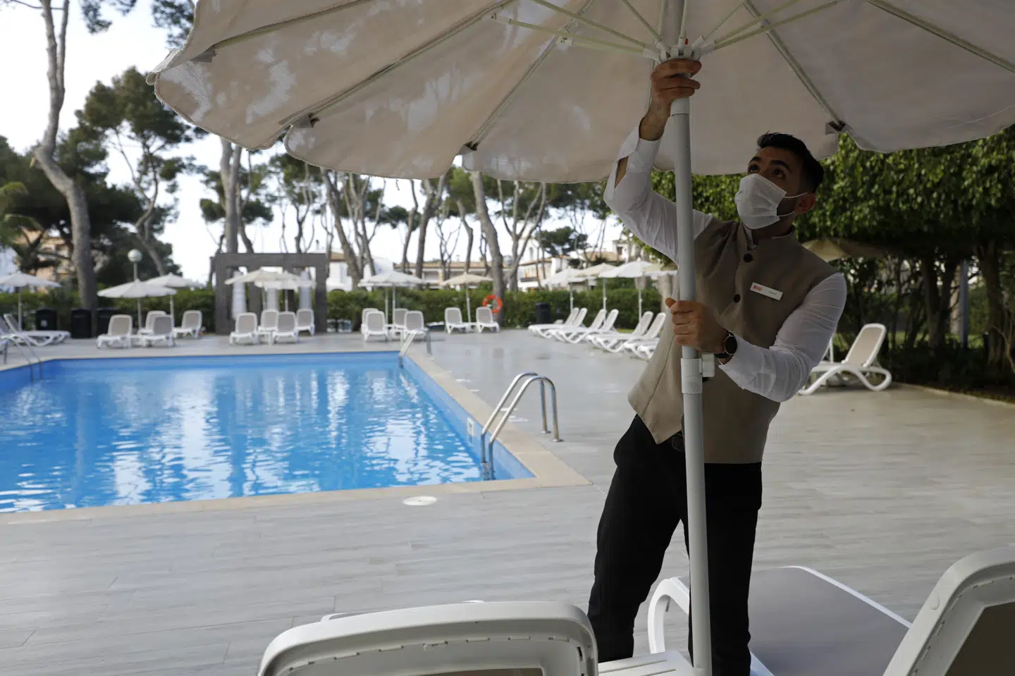 En hotelansat i Palma de Mallorca slår fredag parasollen op, og nu har tyskerne meldt deres ankomst til den spanske ferieø søndag. Lave coronasmittetal gør det muligt. Clara Margais/Ritzau Scanpix