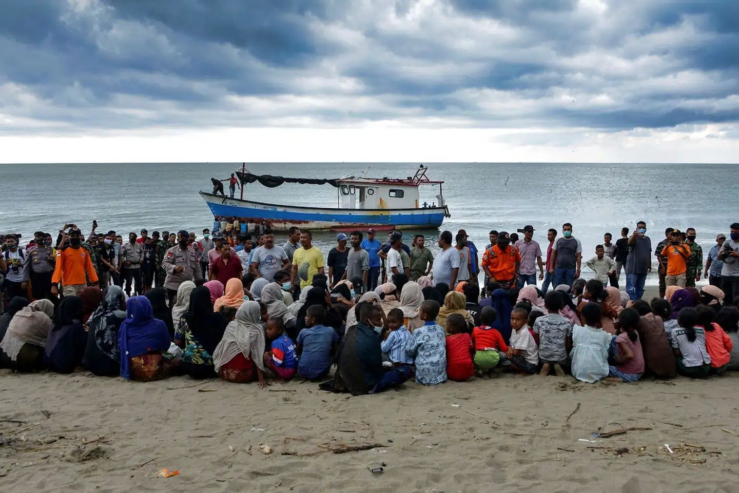 Flygtninge ved landsbyen Lancok sidder på stranden foran den båd, de kom sejlende i til det nordlige Aceh i Indonesien.