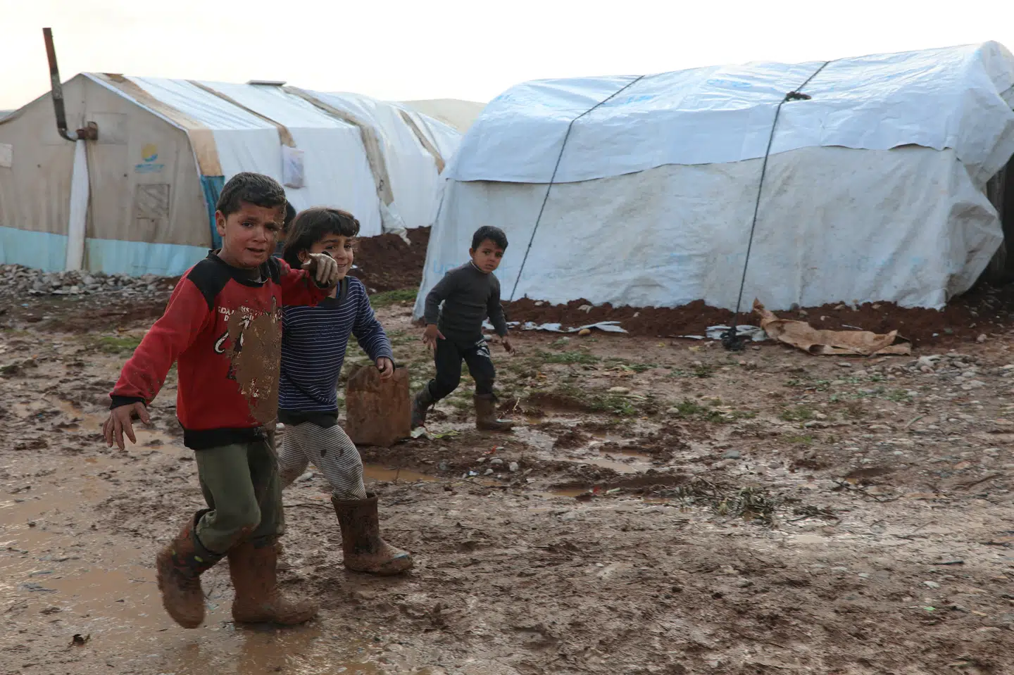 Syriske børn går gennem mudderet i en lejr for internt fordrevne i provinsen Aleppo lørdag. Mahmoud Hassano/Reuters