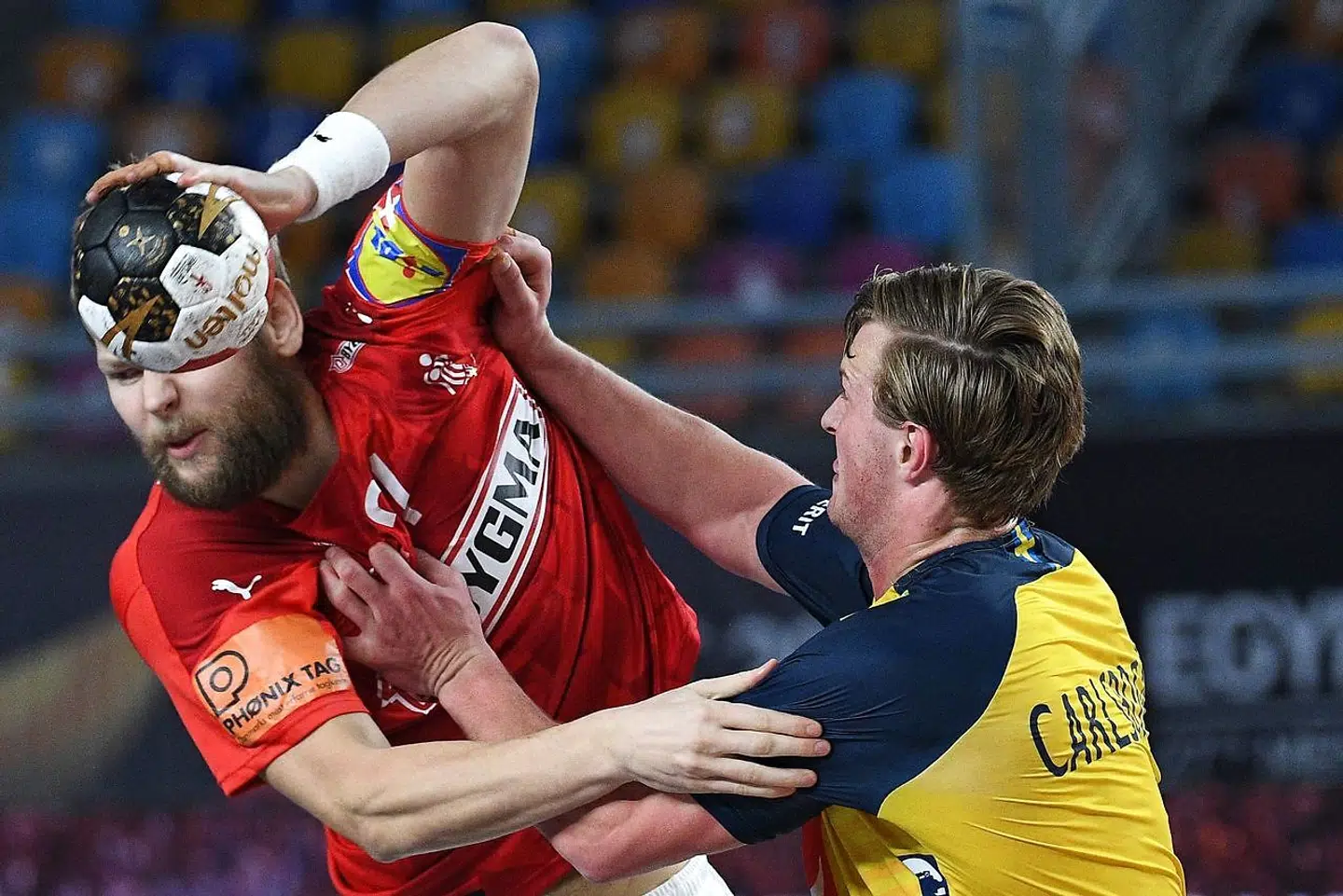 Denmark's right back Nicolaj Oris Nielsen (L) is challenged by Sweden's left back Jonathan Carlsbogard during the 2021 World Men's Handball Championship final match between Denmark and Sweden at the Cairo Stadium Sports Hall in the Egyptian capital on January 31, 2021. (Photo by Anne-Christine POUJOULAT / AFP)