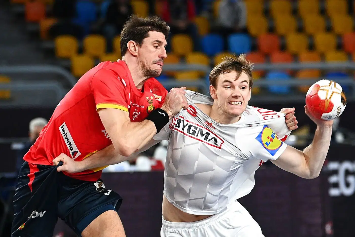 Denmark's right back Mathias Gidsel (R) is challenged by Spain's left back Daniel Dujshebaev (L) during the 2021 World Men's Handball Championship semifinal match between Spain and Denmark at the Cairo Stadium Sports Hall in the Egyptian capital on January 29, 2021. (Photo by Anne-Christine POUJOULAT / AFP)
