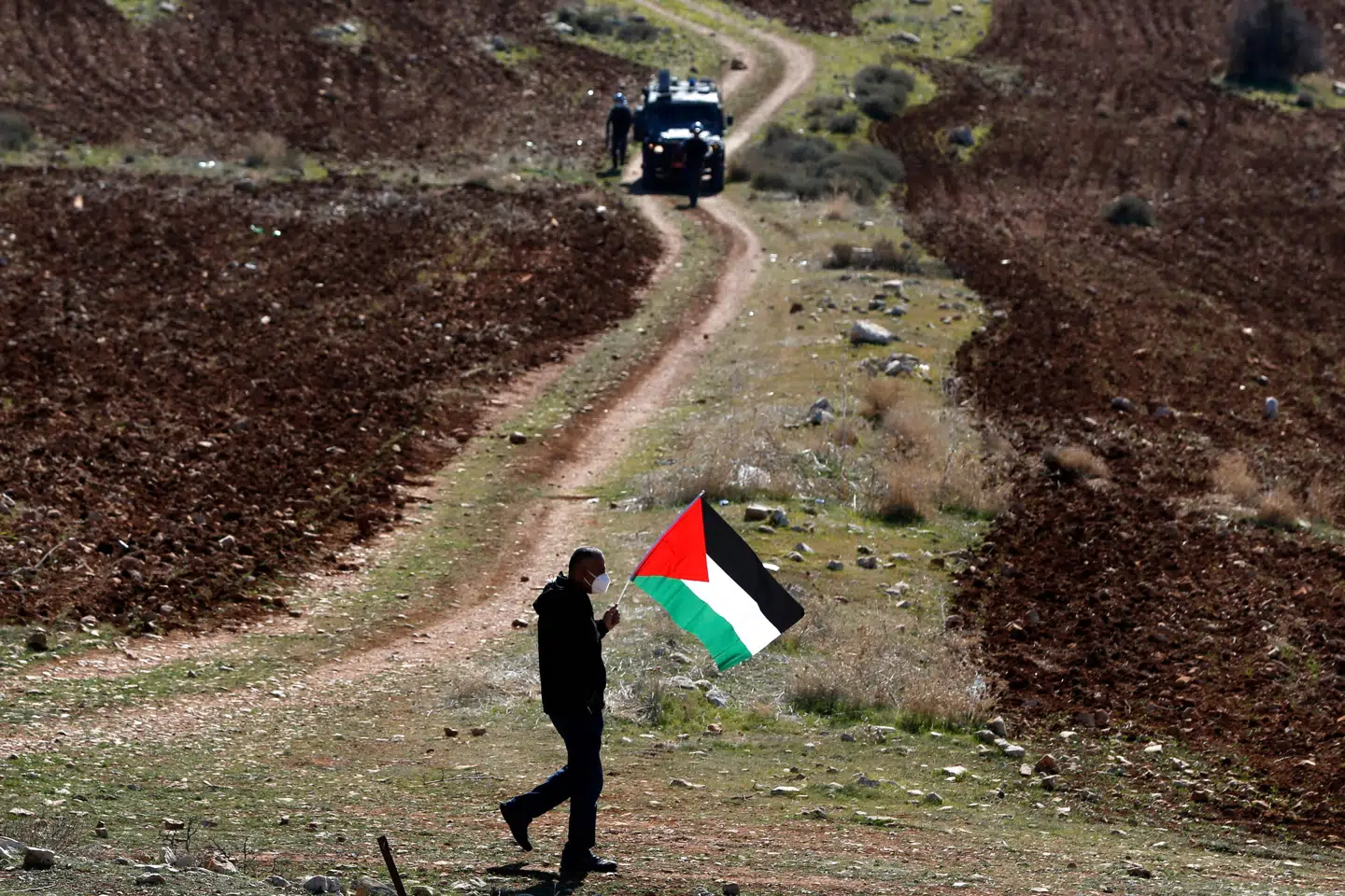 En demonstrant med et palæstinensisk flag i hånden passerer forbi israelske soldater under en demonstration mod Israels bosættelser på Vestbredden i sidste uge. Abbas Momani/Ritzau Scanpix