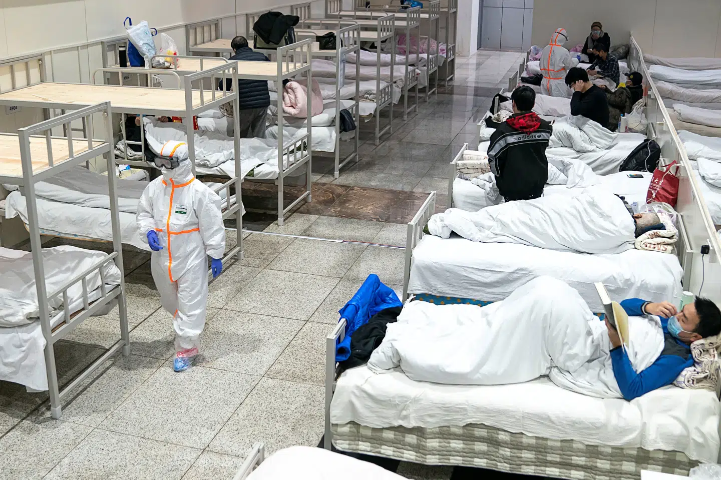 Læger i beskyttelsesdragter tilser viruspatienter i Wuhan i begyndelsen af epidemien. Patienterne her var indlagt på Wuhan International Conference and Exhibition Center, der er blevet omdannet til et midlertidigt behandlingscenter. China Daily/Reuters