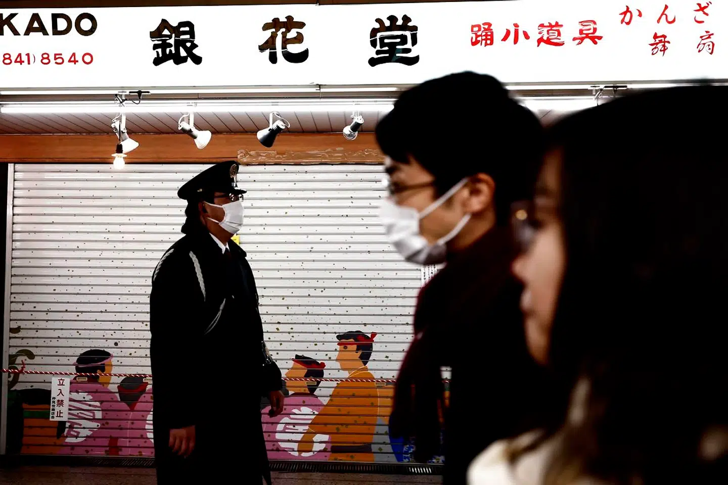 A police officer (L) wearing a face mask to help prevent the spread of the Covid-19 coronavirus walks along Sensoji temple shopping street in the Asakusa district of Tokyo on January 2, 2021. - Tokyo's governor asked the central government to declare a new state of emergency as the country battles a third wave of coronavirus, with the capital reporting record new cases. (Photo by Behrouz MEHRI / AFP)