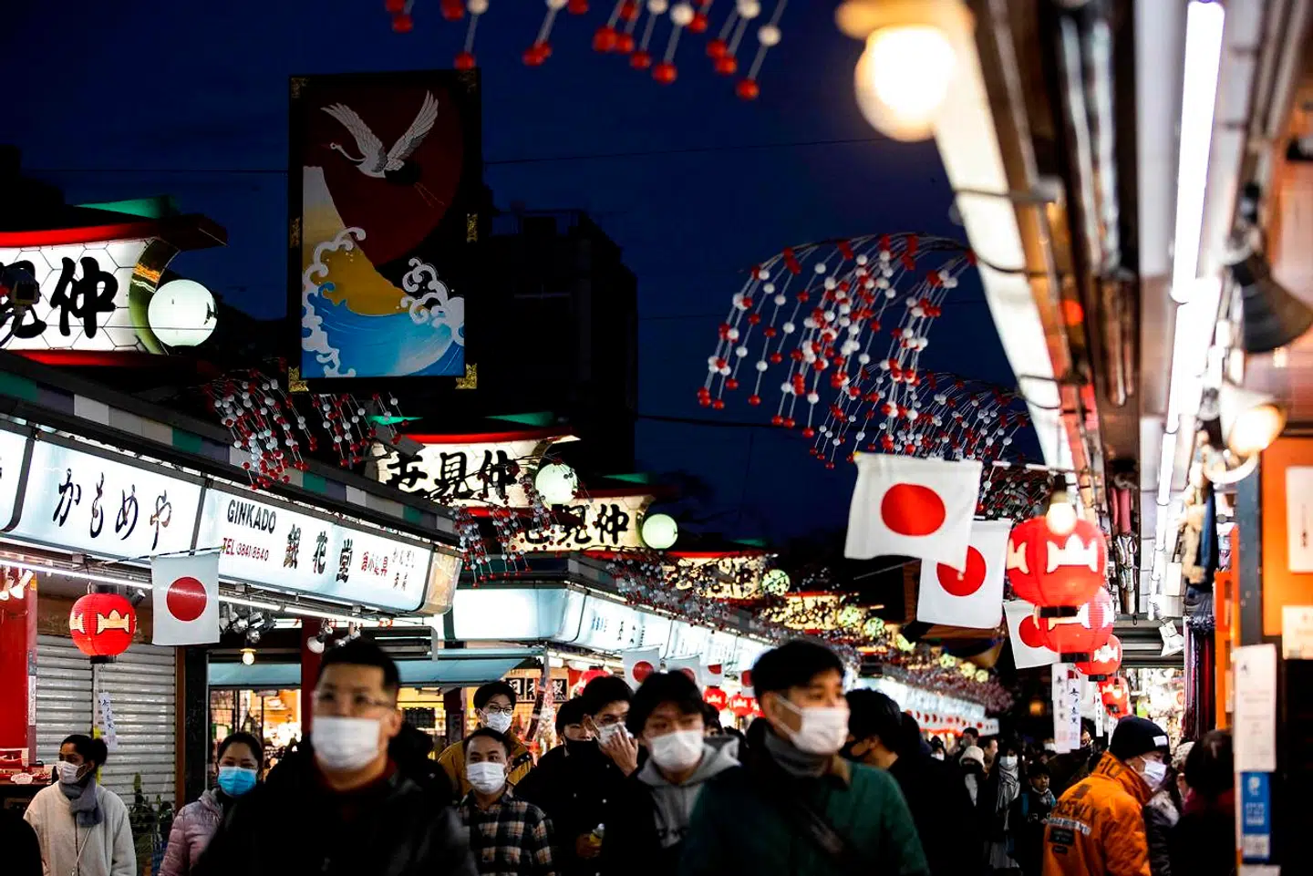 People wearing face masks to help prevent the spread of the Covid-19 coronavirus walk along Sensoji temple shopping street in the Asakusa district of Tokyo on January 2, 2021. - Tokyo's governor asked the central government to declare a new state of emergency as the country battles a third wave of coronavirus, with the capital reporting record new cases. (Photo by Behrouz MEHRI / AFP)