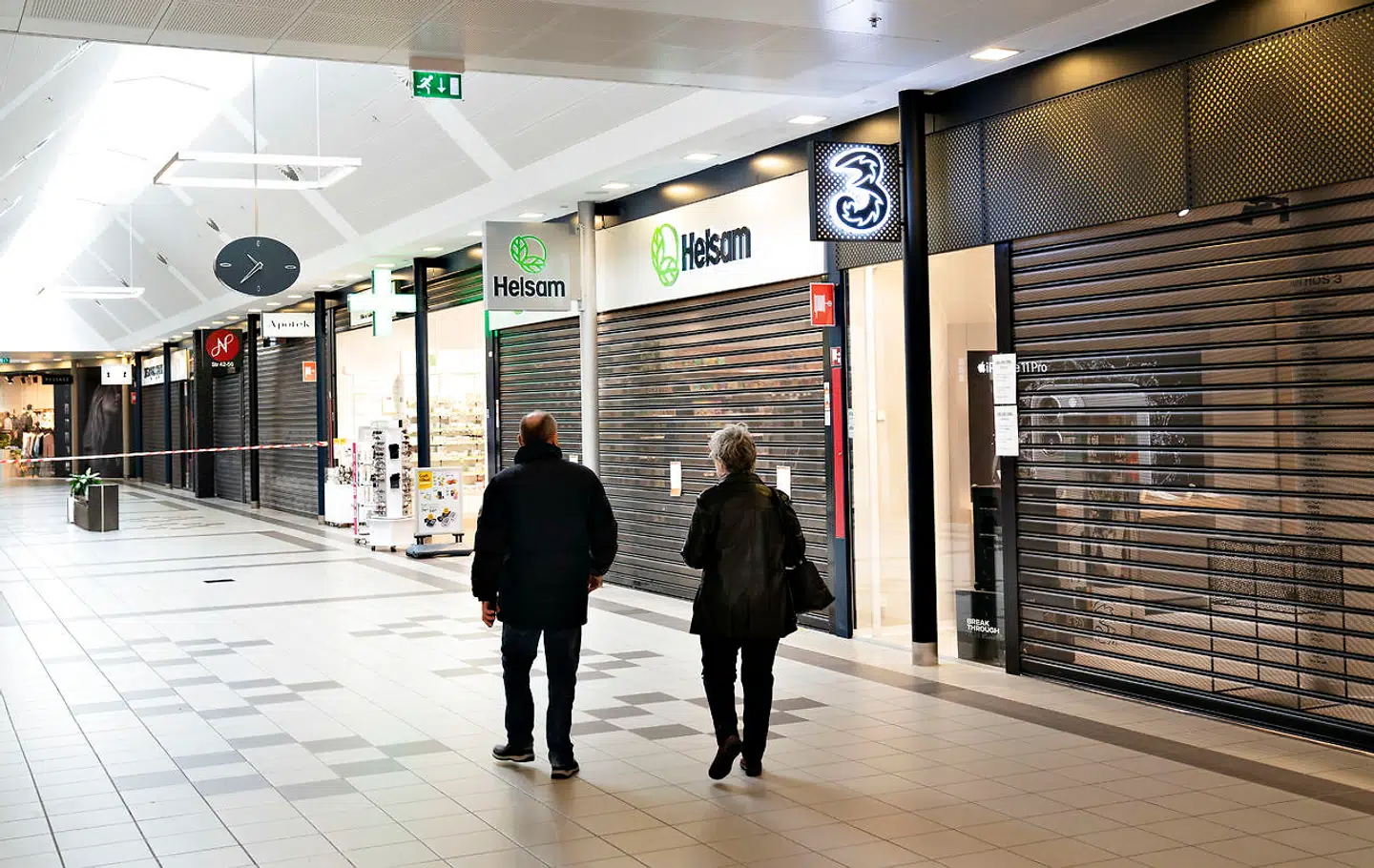Butikkerne i Aalborg Storcenter er lukket ned med skodder, onsdag den 18. marts 2020. Regeringen meddelte tirsdag at natklubber, fitnesscentre, frisører, storcentre og en række andre butikker som følge at COVID-19 skal holde lukket fra onsdag kl.10. Fødevarebutikker er undtaget, oplyser statsministeren. På billederne er der kunder fra Bilka Storcenter og et apotek der holder åbent.. (Foto: Henning Bagger/Ritzau Scanpix)