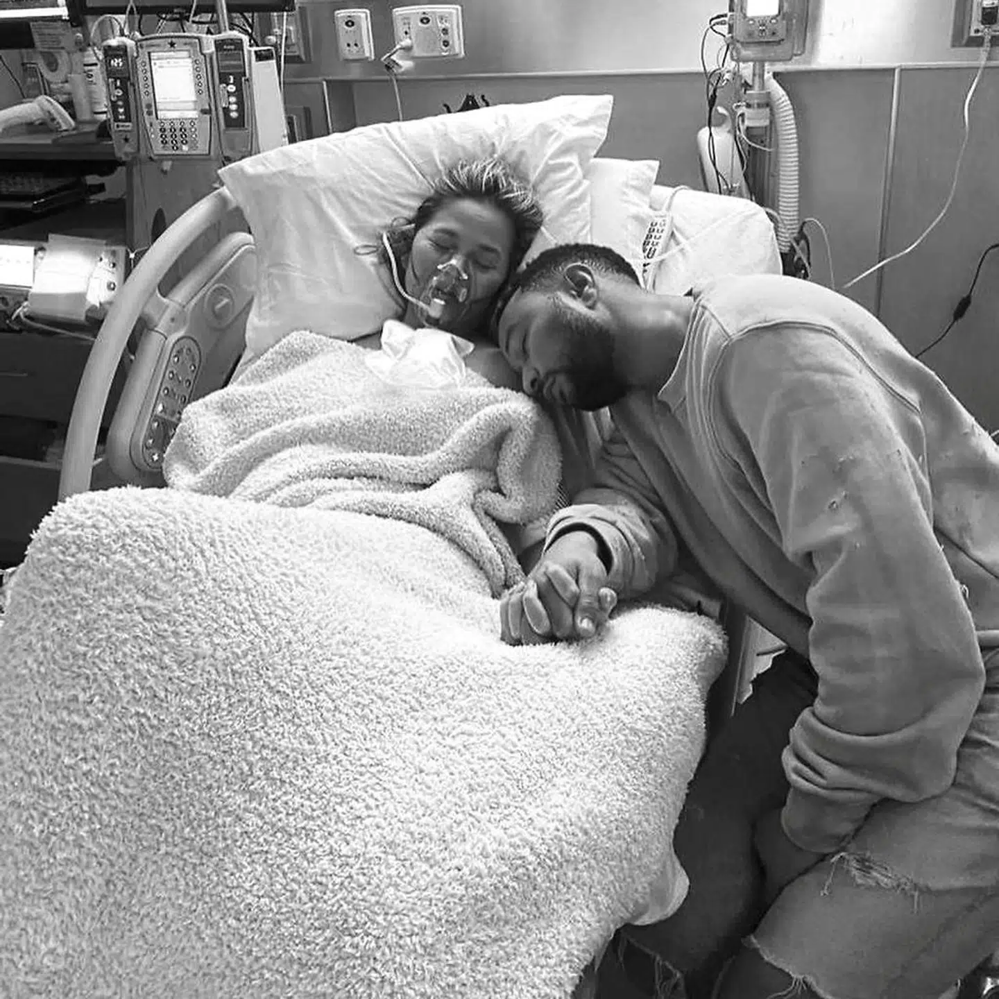 Chrissy Teigen med John Legend ved sin side i hospitalssengen.