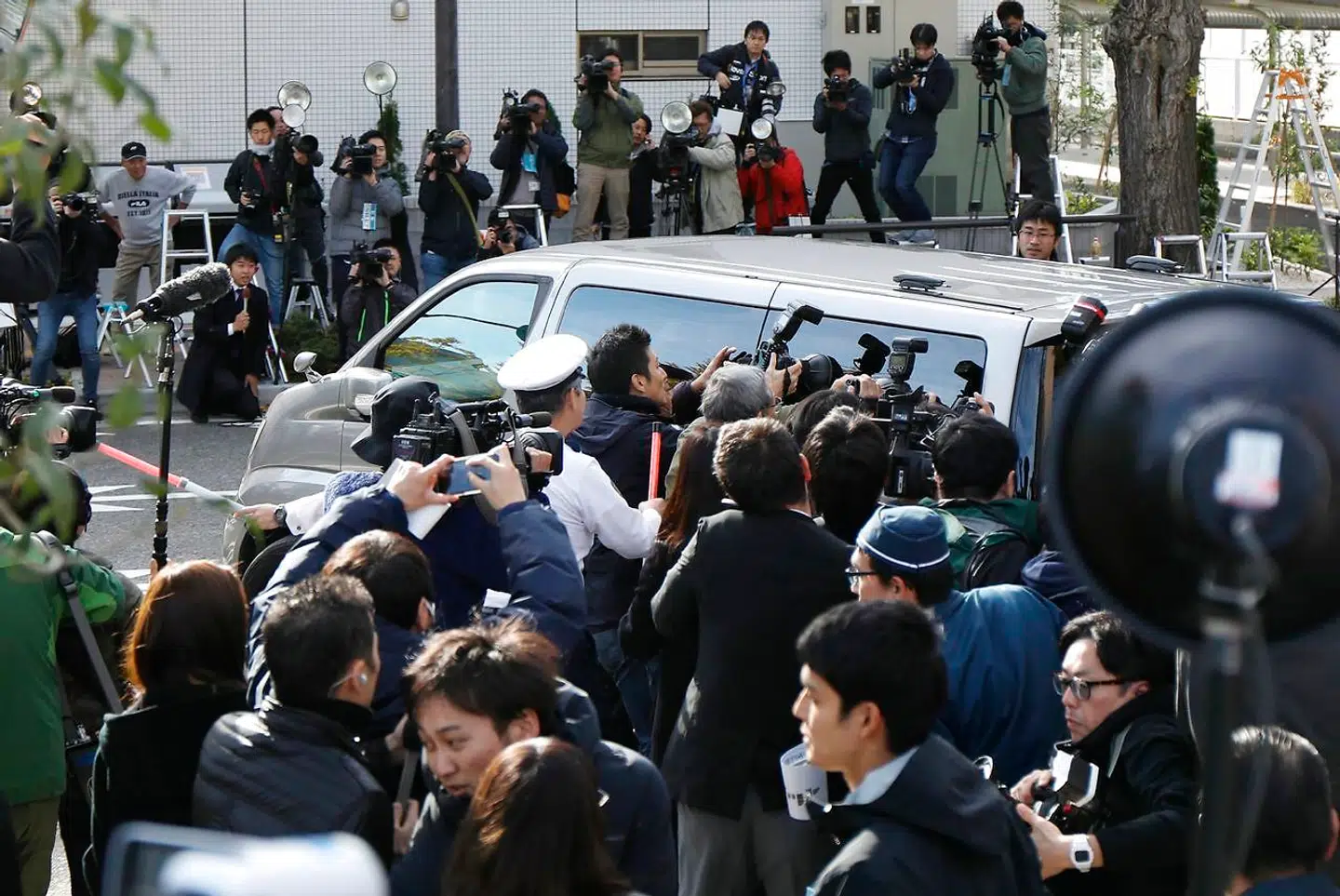Pressefotografer flokkes om bilen, som transporterede Takahiro Shiraishi væk fra politistaionen i Tokyo kort efter anholdelsen i 2017.