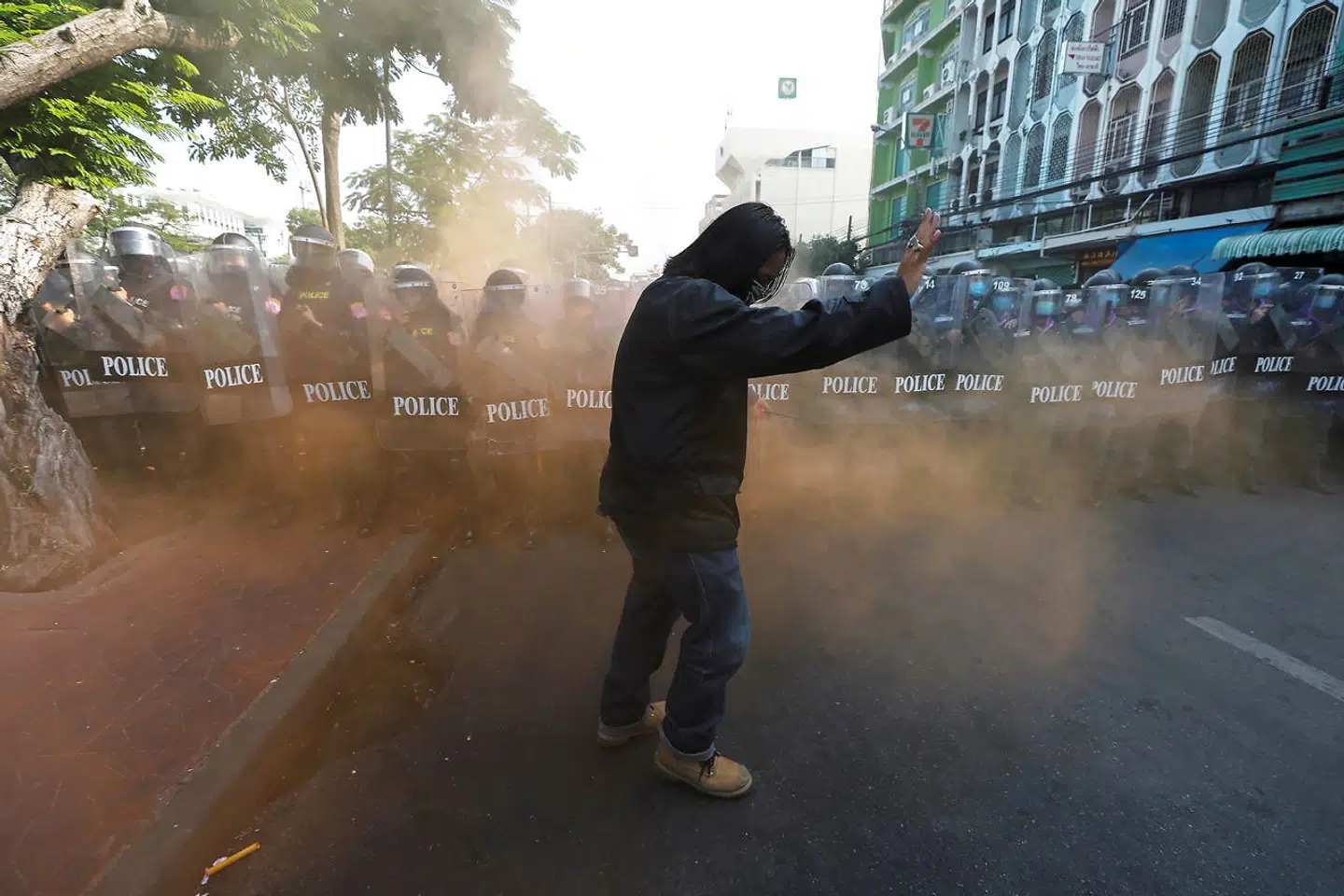 Denne demonstrant reagerer på en røgbombe, der er smidt af en anden demonstrant, men politifolk står vagt.
