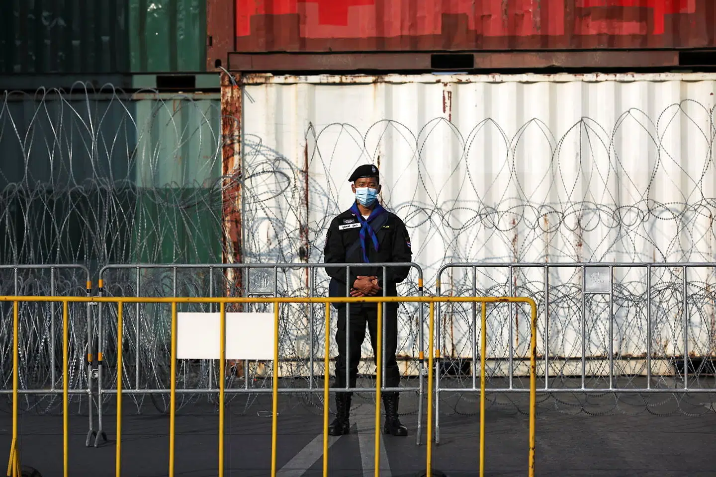En politimand står vagt ved nogle skibscontainere, der er sat op for at forhindre demonstranterne i at komme frem.