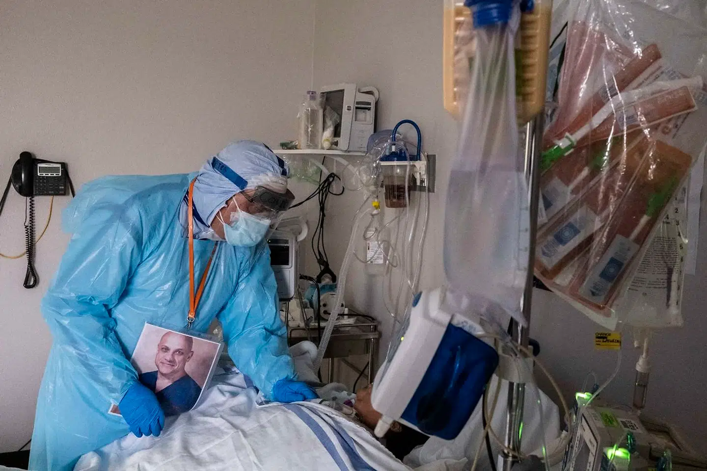 Rundt om halsen har lægen et billede af sig selv hængende, så patienterne kan se, hvordan han ser ud inde under masken.